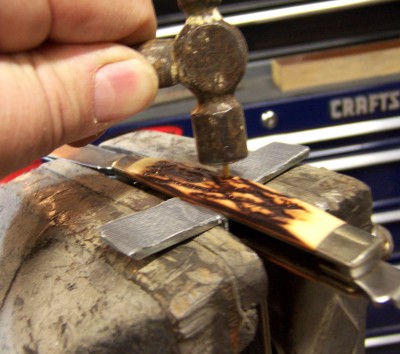 Tap the pin gently until it seats into the bevel around the hole in the handle.<br />This step may be omitted on many knives.  I have had several knives that I was able to push the pin all the way down to where the head seated on the handle with just pressure from my finger.