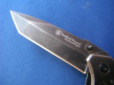 Smith & Wesson Folding knife CK404 & 1975 Smith & Wesson 'The Hostiles' Brass Belt Buckle. Smith & Wesson Folding knife CK404 & 1975 Smith & Wesson 'The Hostiles' Brass Belt Buckle.