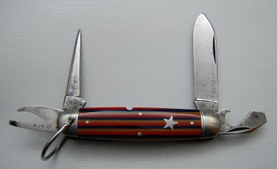 Remington UMC Circle #3335, Red, Tan &amp; Blue Celluloid Covers, 3 3/4” closed<br />Spear blade is 95% full, lined nickel silver bolsters and a perfect bail<br />Inlaid star shield and a full awl make this a very fine example of a very rare knife!