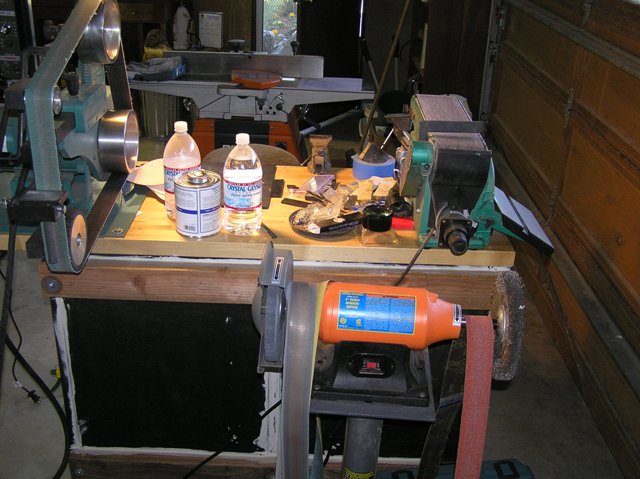 View of a bench, there is 2 in the shop. A couple vices, 5 different vices throughout the shop. 4 x 36 sander and a grinder with a wire wheel